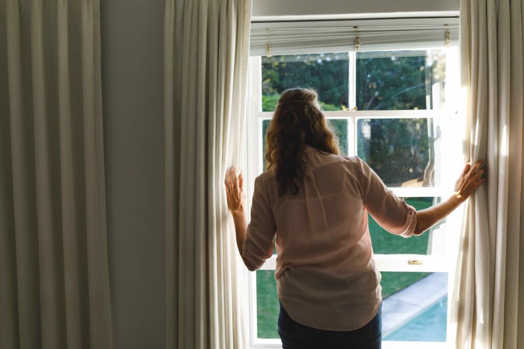 Woman opening curtains.