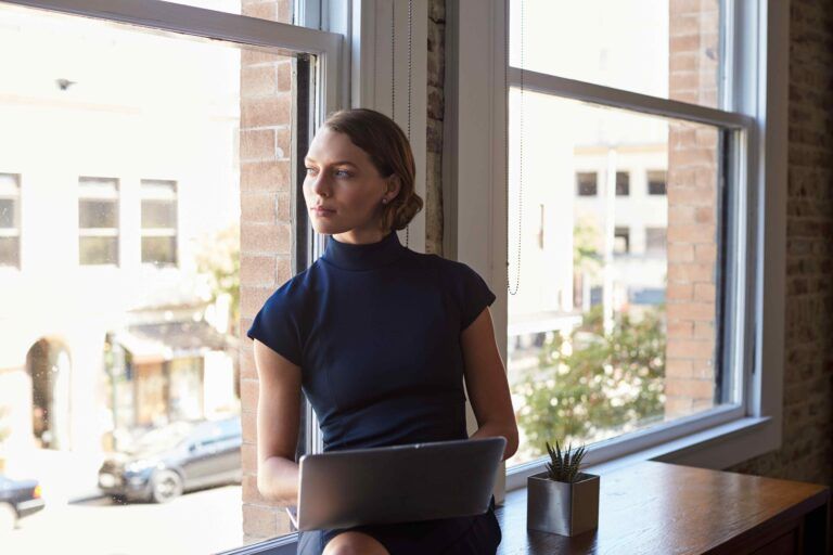 Woman sitting with laptop by the window