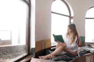 Woman reading book in front of window