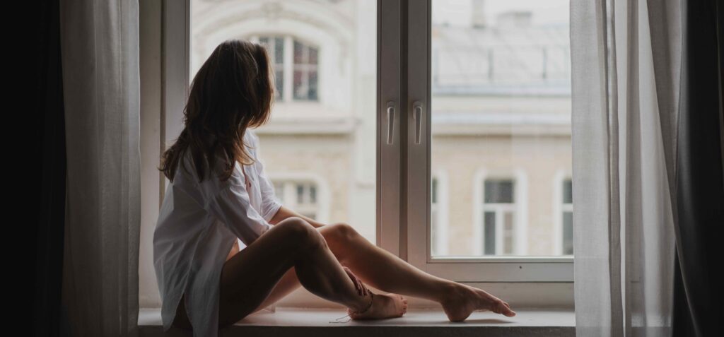 Young woman sitting on front of window