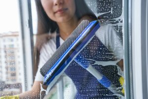 Young woman cleaning window with squeegee